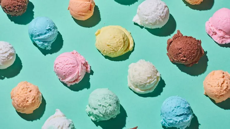 Multiple colorful ice cream scoops arranged in a grid pattern on a vibrant green background, showcasing a variety of flavors including chocolate, vanilla, and fruity options.